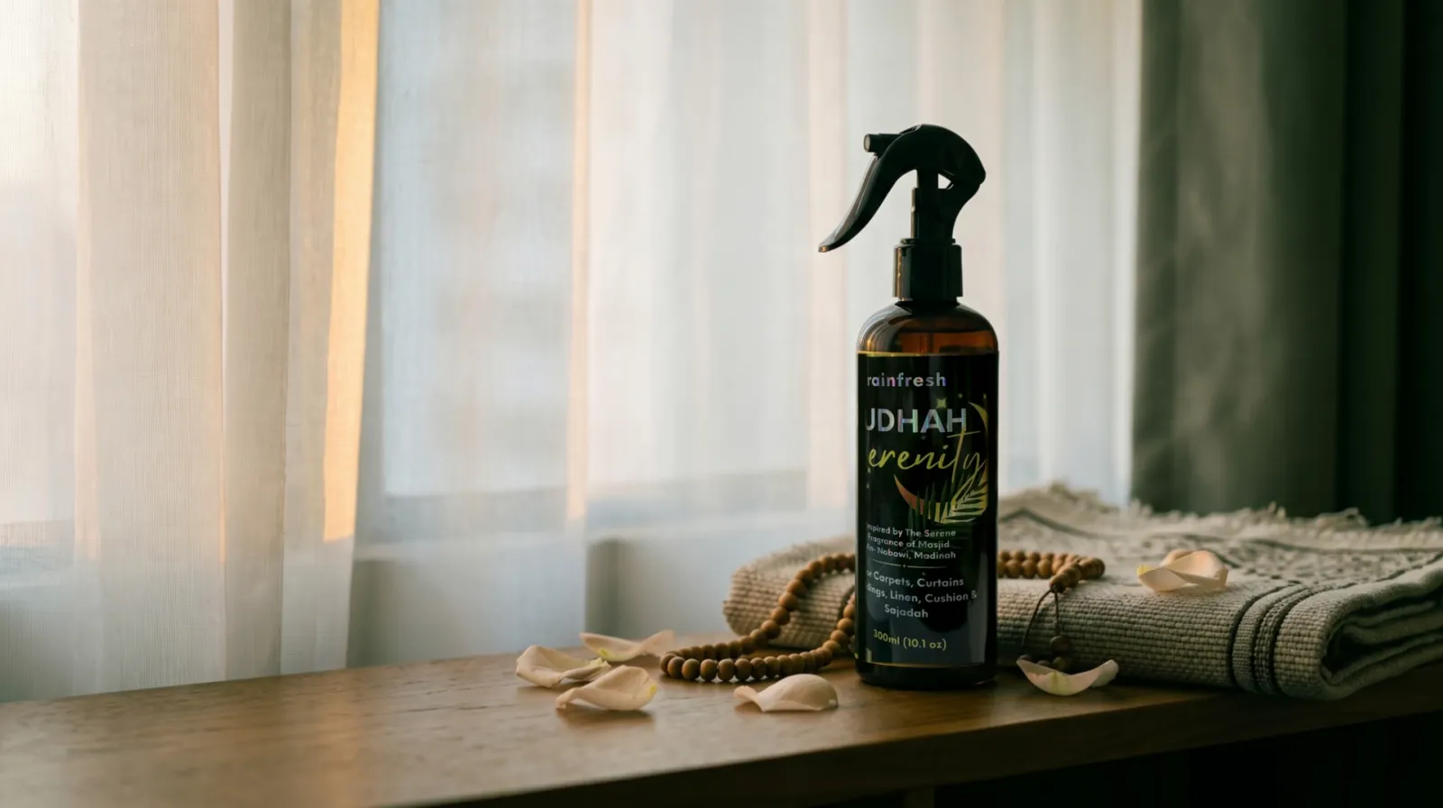 Raudhah Serenity spray beside a folded prayer mat, wooden prayer beads and rose petals, soft window light